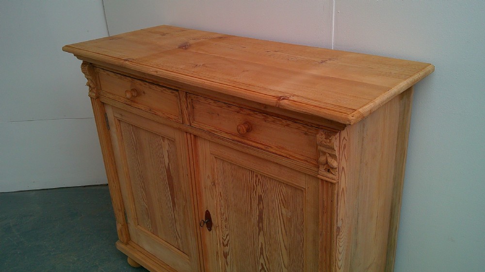 An early Victorian stripped pine shallow dresser base featuring two top drawers over a two-door panelled cupboard with turned bun feet. View VI