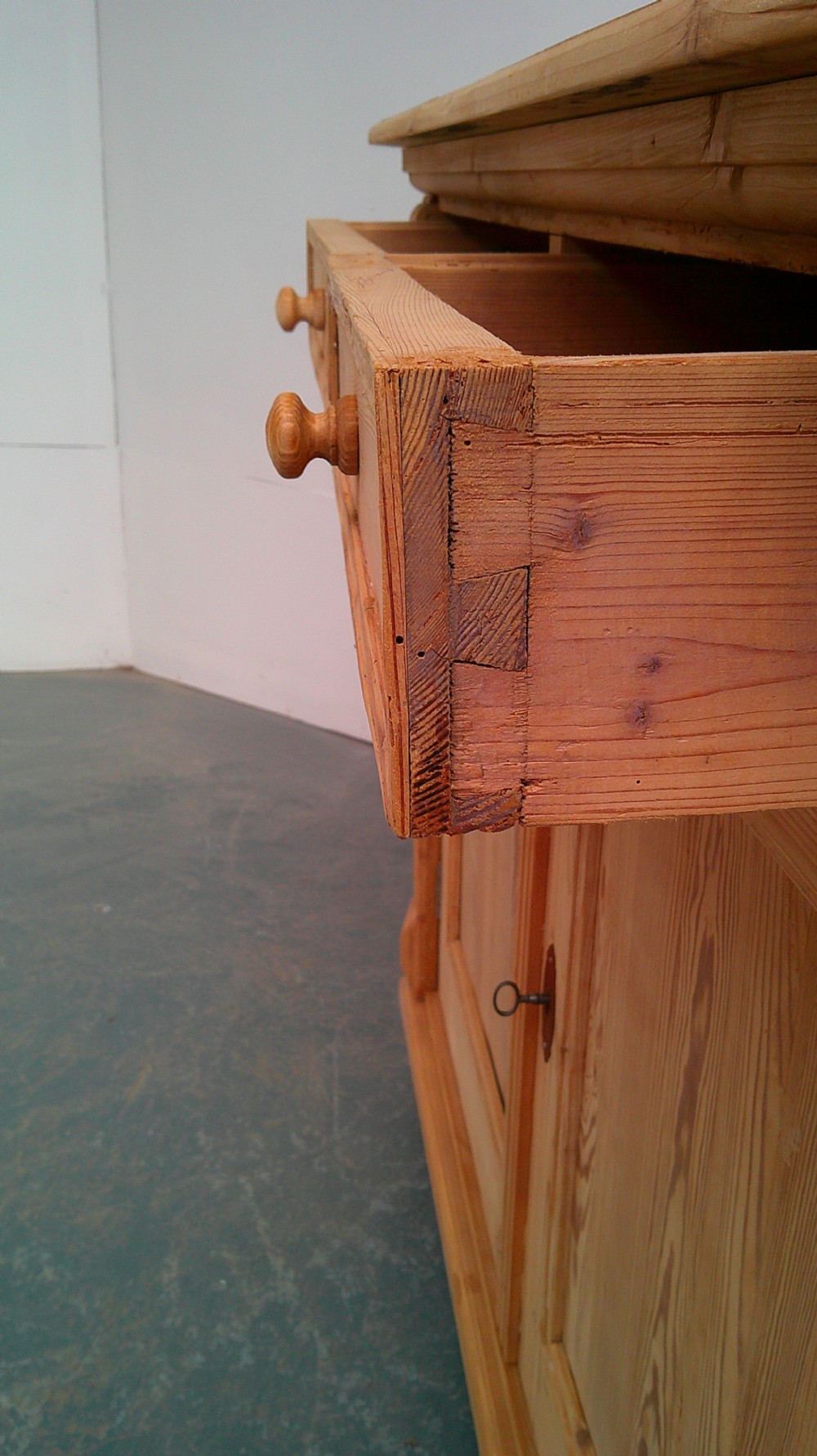 An early Victorian stripped pine shallow dresser base featuring two top drawers over a two-door panelled cupboard with turned bun feet. View VII