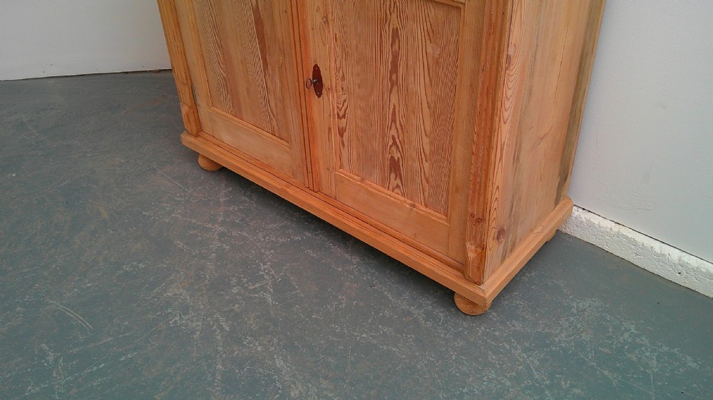 An early Victorian stripped pine shallow dresser base featuring two top drawers over a two-door panelled cupboard with turned bun feet. View VIII