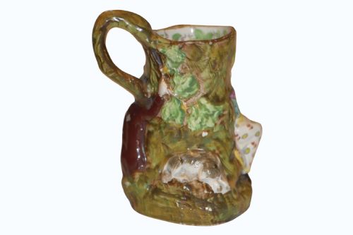 fig 1. An 18th-century Staffordshire pearlware Fair Hebe jug featuring relief-moulded figures around a tree trunk with a branch-shaped handle.