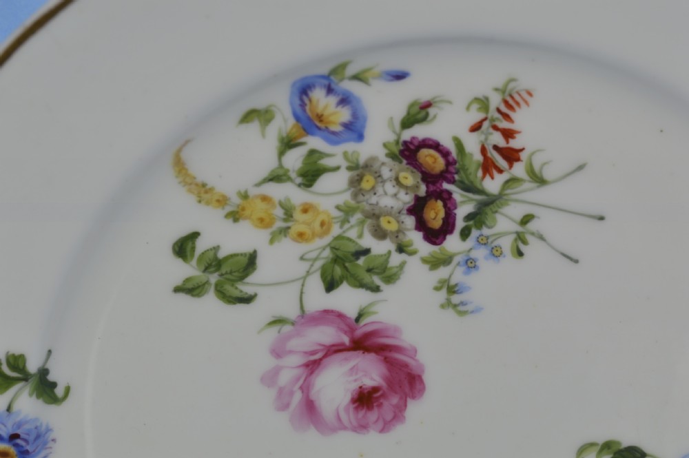 A white circular porcelain plate featuring a scalloped gilt rim and hand-painted botanical floral sprays across the surface. View II