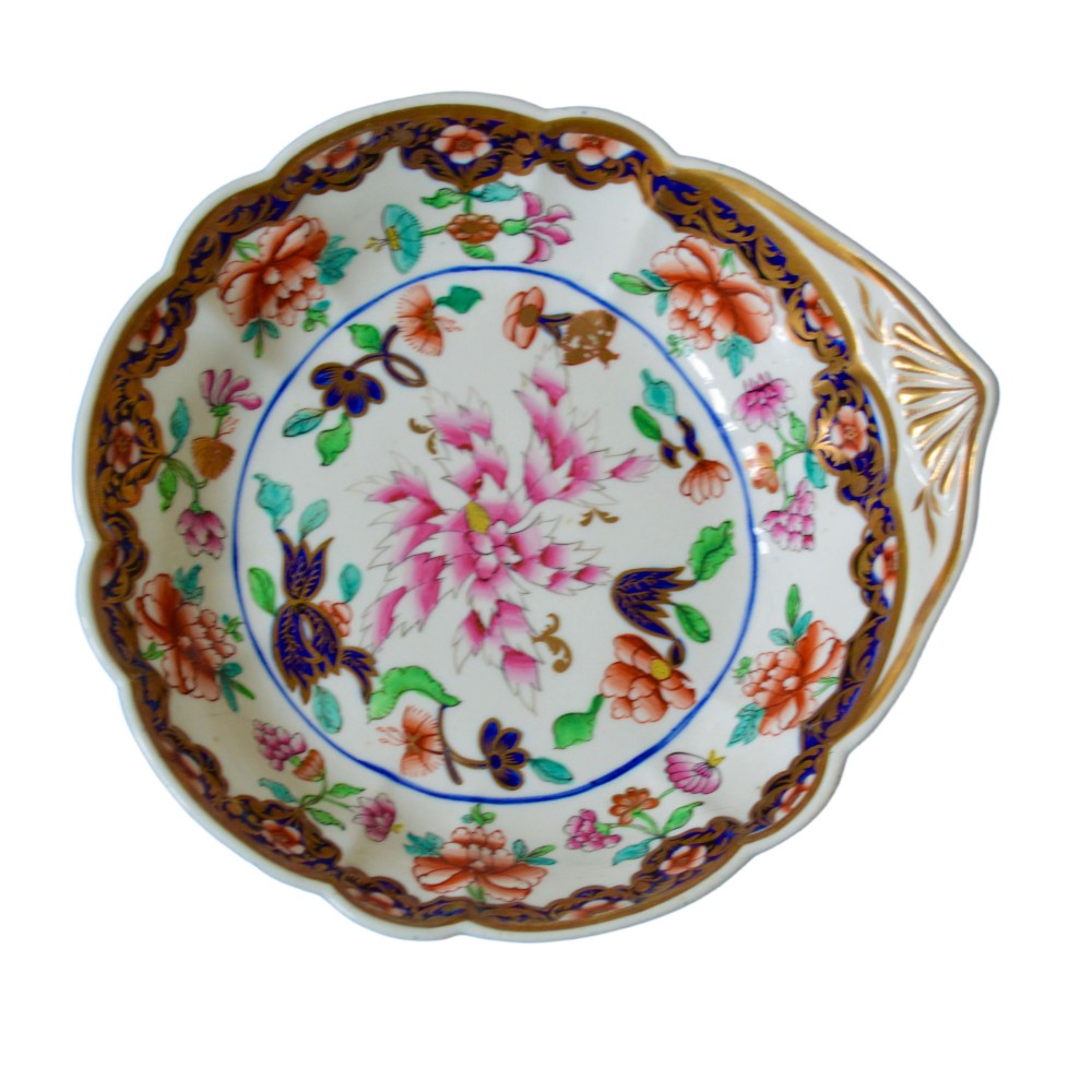 A Regency Swansea porcelain dessert dish with a scalloped edge, shell form handle, hand-painted pink floral central motif, and cobalt blue and gilt rim pattern.