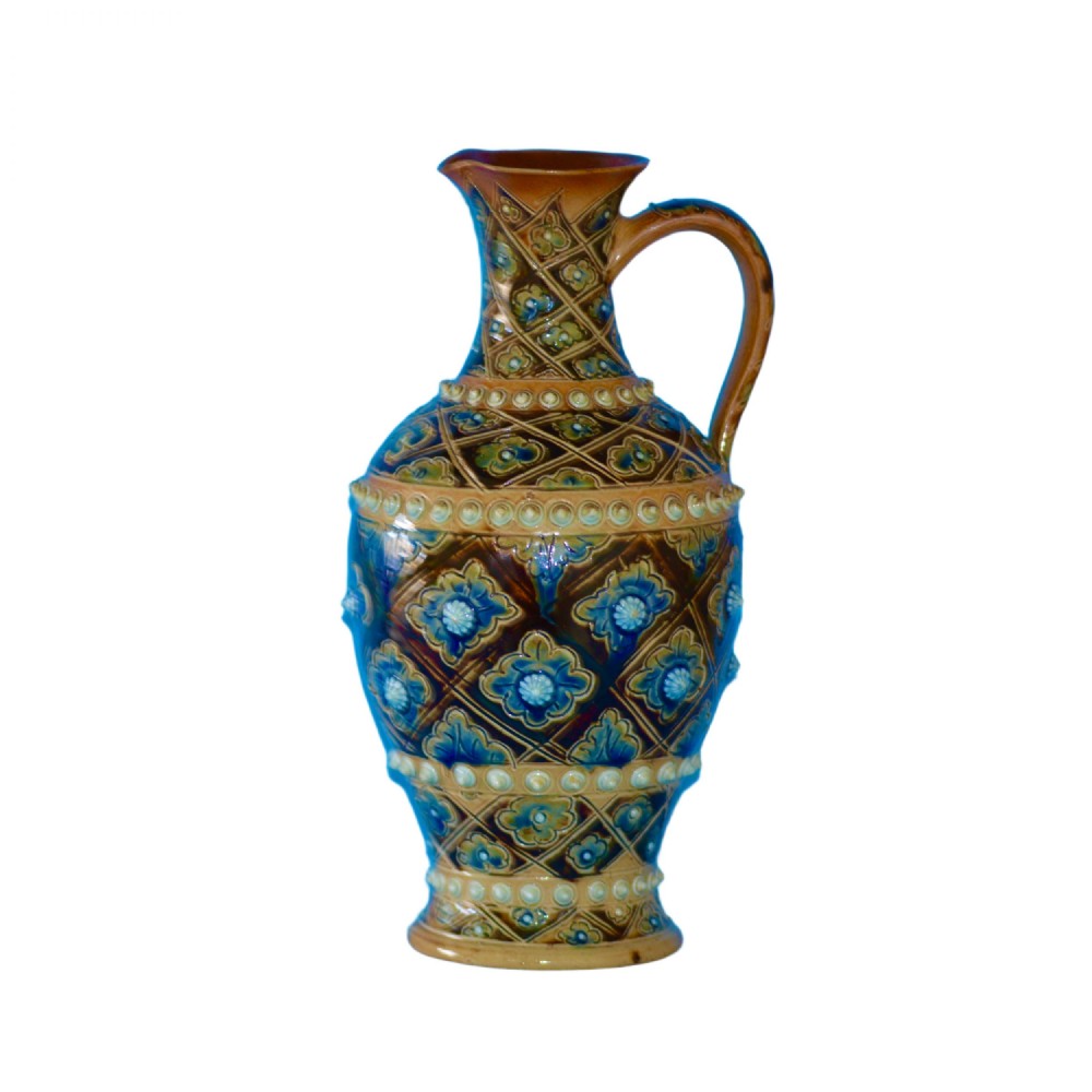 A Victorian salt-glazed stoneware jug featuring geometric diamond relief patterns, blue glazed floral rosettes, raised beaded banding, and a single handle.
