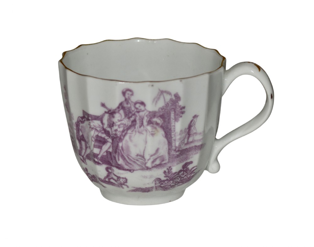 A white fluted porcelain coffee cup decorated with a purple transfer-printed scene of a seated couple in a garden setting, featuring a single loop handle and gilded rim.