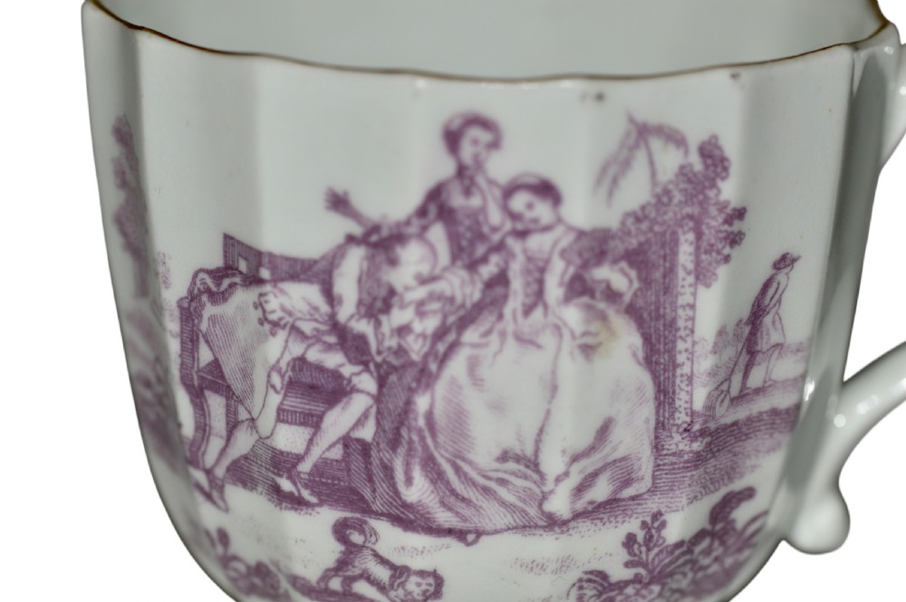 A white fluted porcelain coffee cup decorated with a purple transfer-printed scene of a seated couple in a garden setting, featuring a single loop handle and gilded rim. View V
