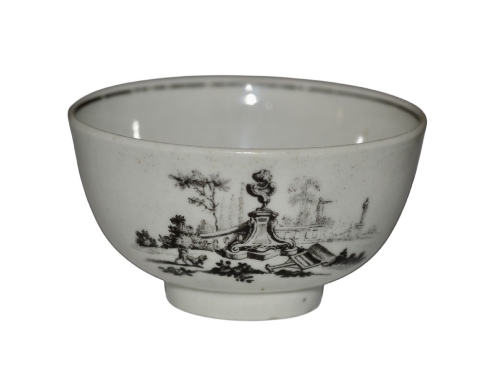 An eighteenth-century off-white soft-paste porcelain tea bowl featuring a black monochrome transfer-printed garden scene around its exterior.