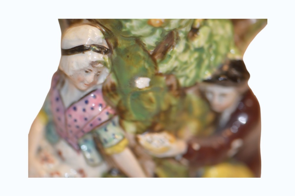 An 18th-century Staffordshire pearlware Fair Hebe jug featuring relief-moulded figures around a tree trunk with a branch-shaped handle. View V