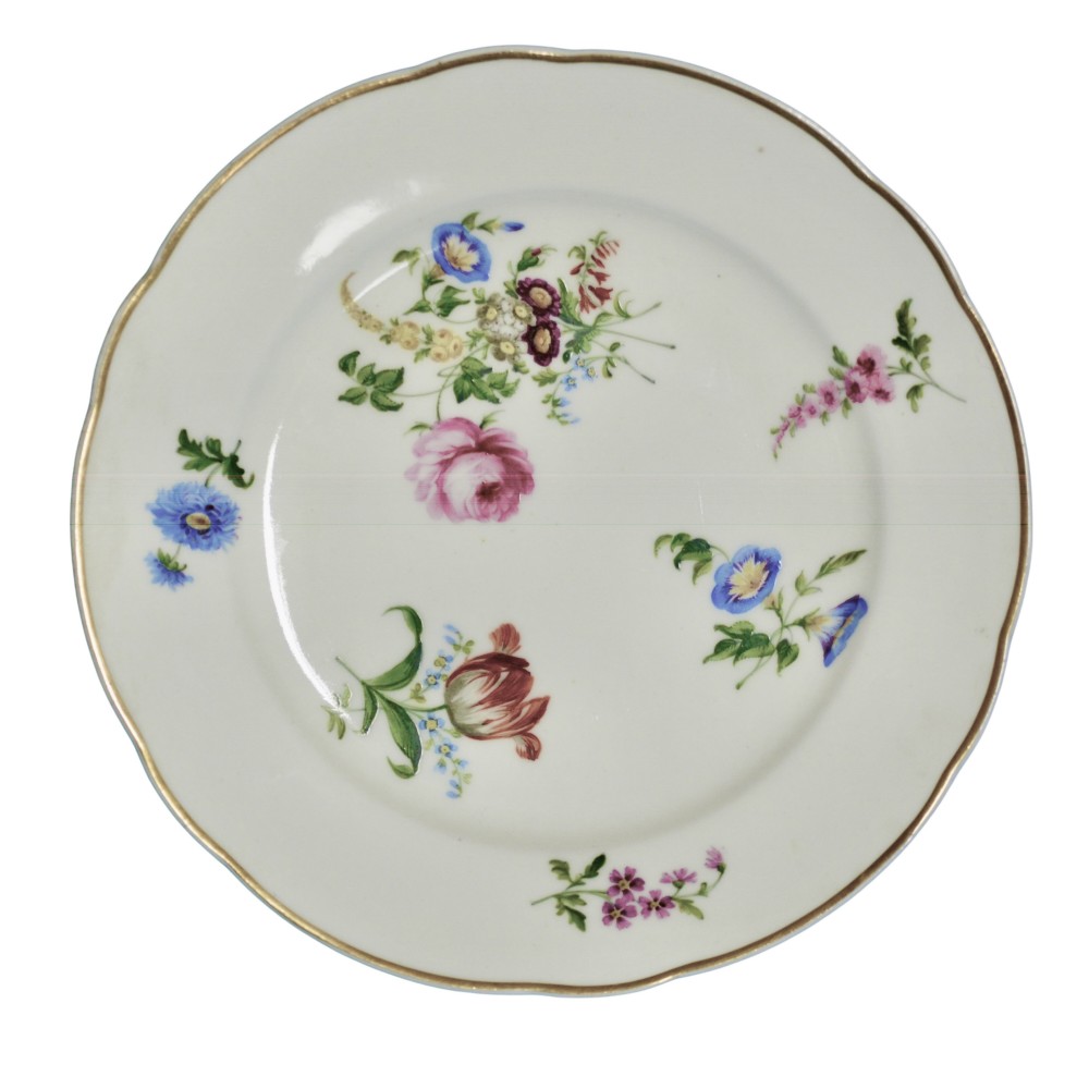 A white circular porcelain plate featuring a scalloped gilt rim and hand-painted botanical floral sprays across the surface.