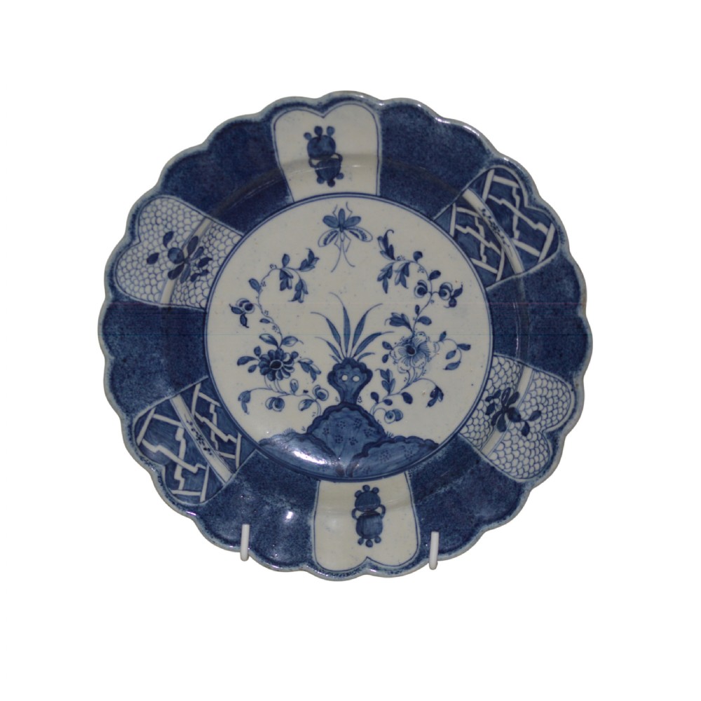 A circular eighteenth-century Caughley porcelain dessert dish featuring a scalloped rim, underglaze cobalt blue Scholars Rock motif, and panelled diaper borders.