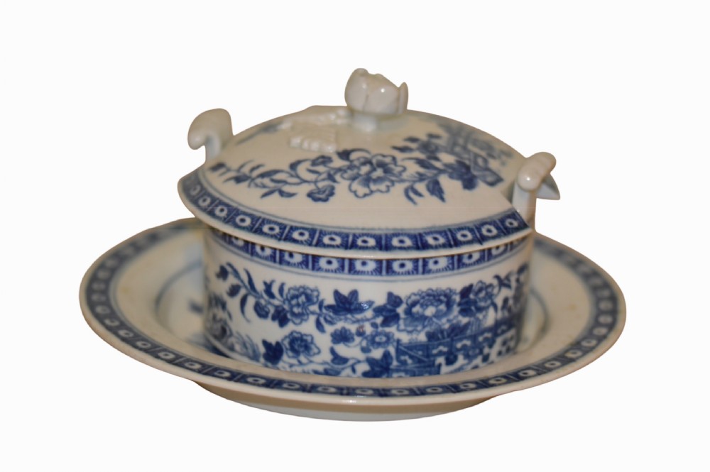 An 18th-century Dr Wall Worcester blue and white porcelain butter tub with a lid featuring a sculpted flower finial, resting on a matching oval stand. View VI