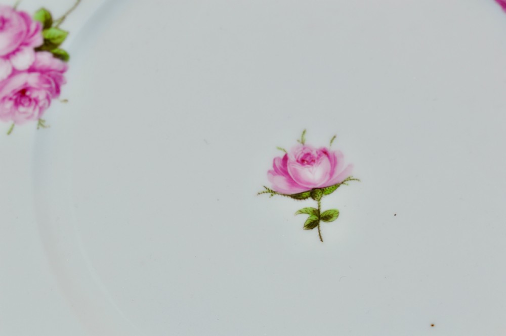 A circular white porcelain plate featuring hand-painted pink rose sprays around the border and in the centre, finished with a gilded rim. View II