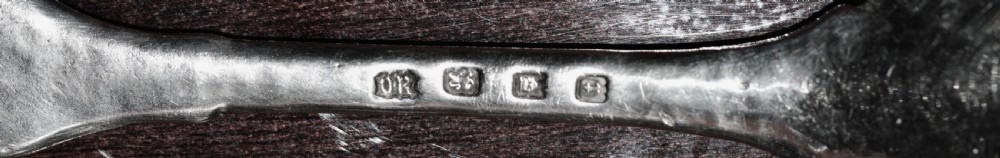 A sterling silver spoon featuring a hand-hammered bowl and an intricately carved decorative terminal with stylised floral motifs. View III