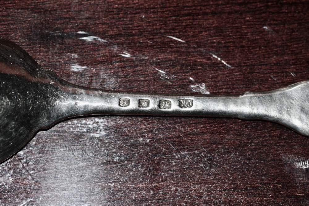 A sterling silver spoon featuring a hand-hammered bowl and an intricately carved decorative terminal with stylised floral motifs. View IV