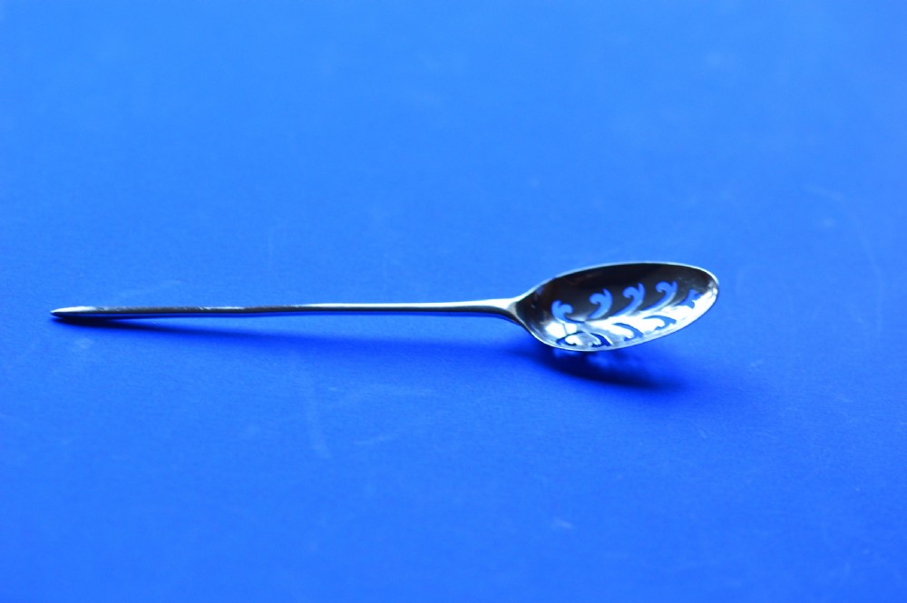 An 18th-century silver mote spoon featuring a hand-pierced oval bowl and a long tapered stem ending in a sharp point. View XII