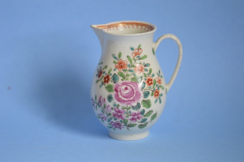 An 18th-century soft-paste porcelain sparrow beak cream jug with hand-painted pink and orange floral sprigs on a white ground.