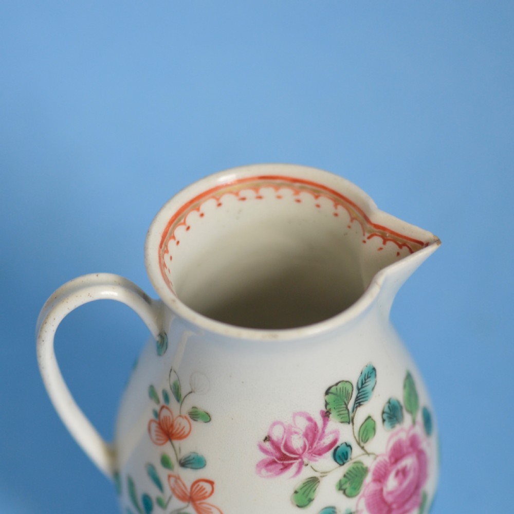 An 18th-century soft-paste porcelain sparrow beak cream jug with hand-painted pink and orange floral sprigs on a white ground. View X