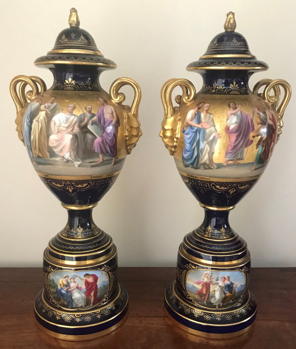 A pair of cobalt blue and gilded Vienna porcelain urns with hand-painted classical mythological figure panels and matching bases. View II