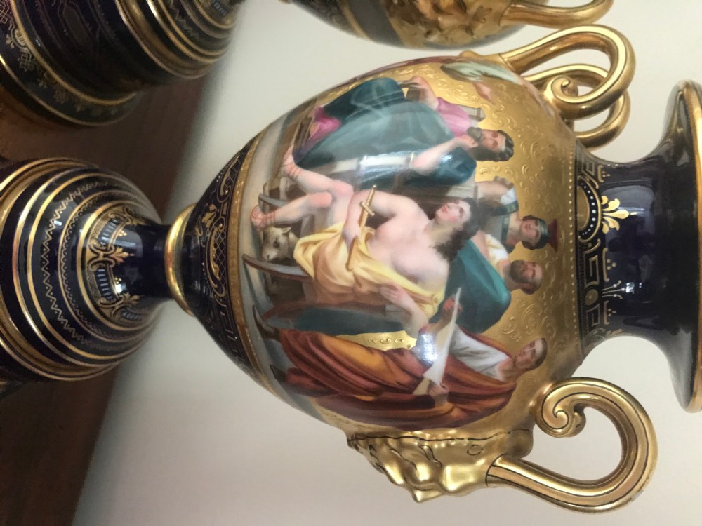 A pair of cobalt blue and gilded Vienna porcelain urns with hand-painted classical mythological figure panels and matching bases. View VII