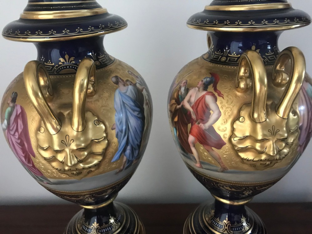 A pair of cobalt blue and gilded Vienna porcelain urns with hand-painted classical mythological figure panels and matching bases. View IX