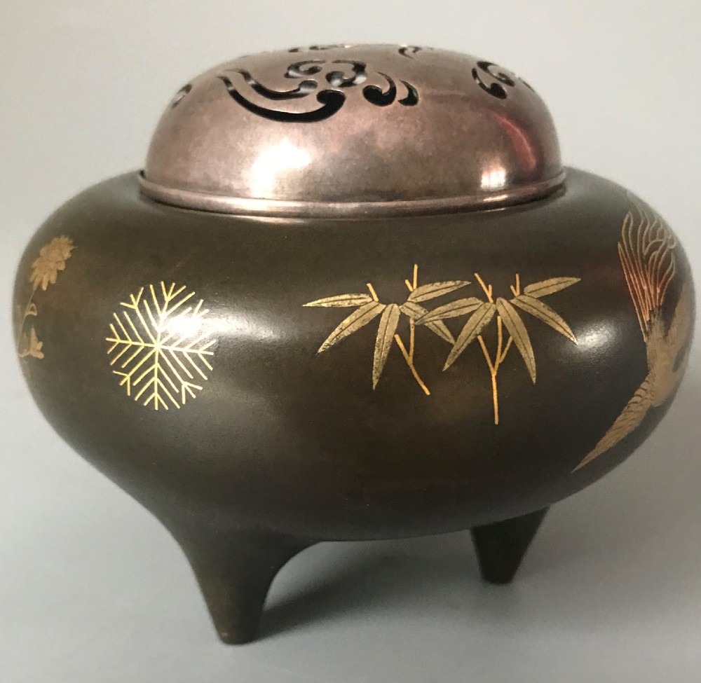 A tripod dark bronze incense burner featuring gold inlaid phoenix bird motifs and a pierced silver lid. View II