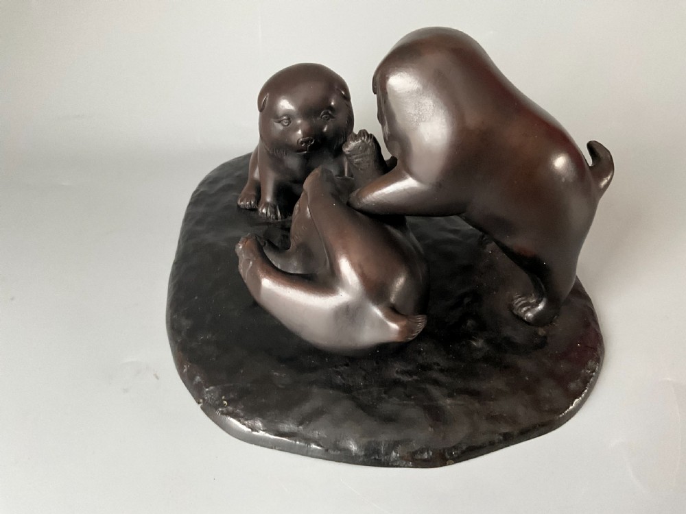 A dark brown patinated bronze Japanese okimono sculpture depicting three playful puppies on a textured base. View II