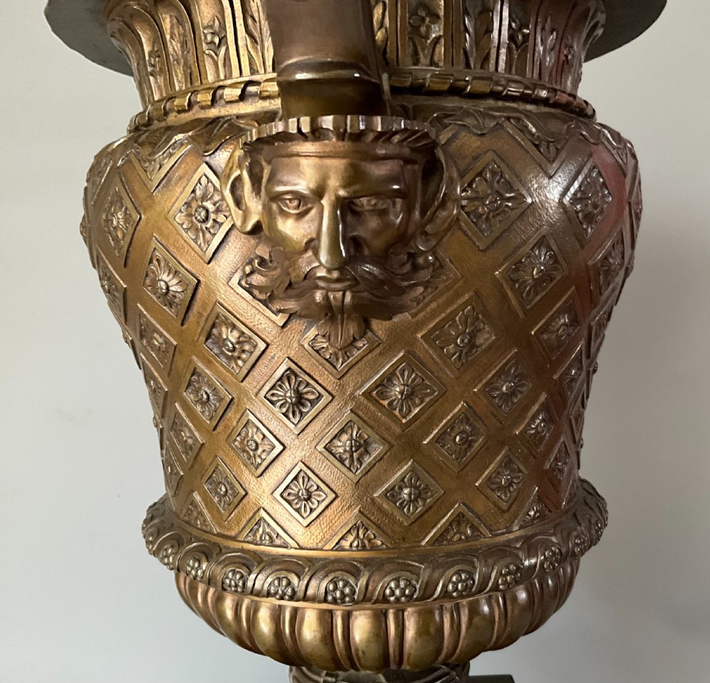 A patinated bronze urn with beast-head handles and a diaper pattern body, mounted on a square red marble plinth. View III