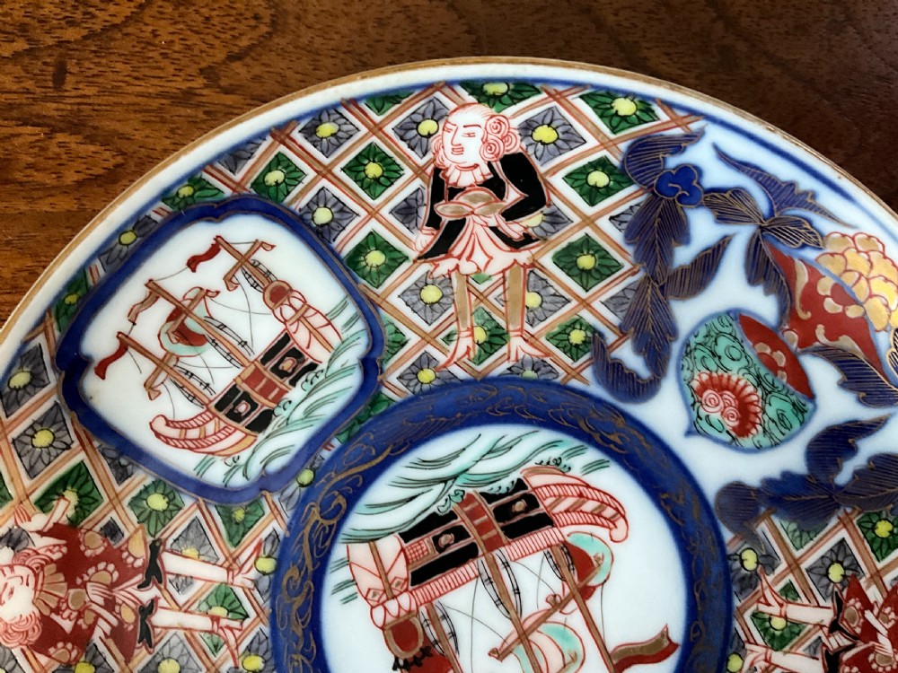 A trio of circular Japanese Imari porcelain plates featuring hand-painted European ships, figures, and geometric patterns in cobalt blue, iron red, green, and gold. View III