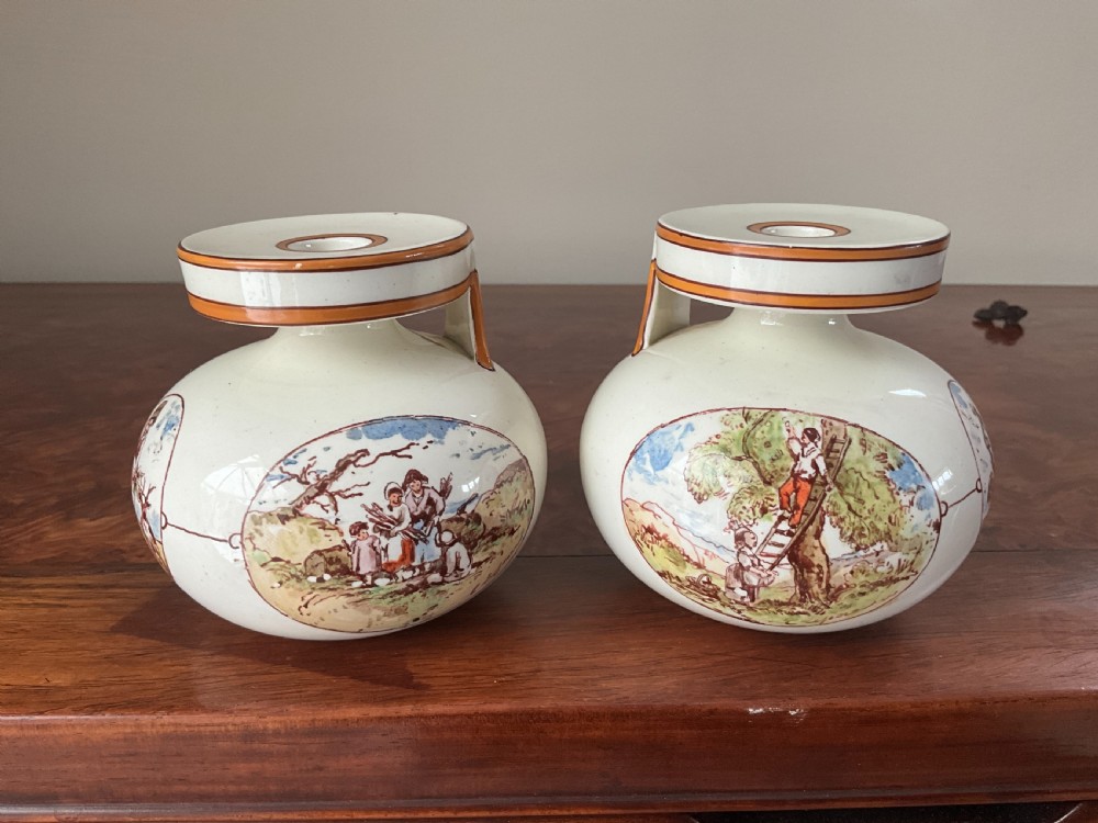 A pair of bulbous cream earthenware vases with orange-trimmed tops, decorated with painted oval cartouches depicting rural agricultural harvest scenes. View II