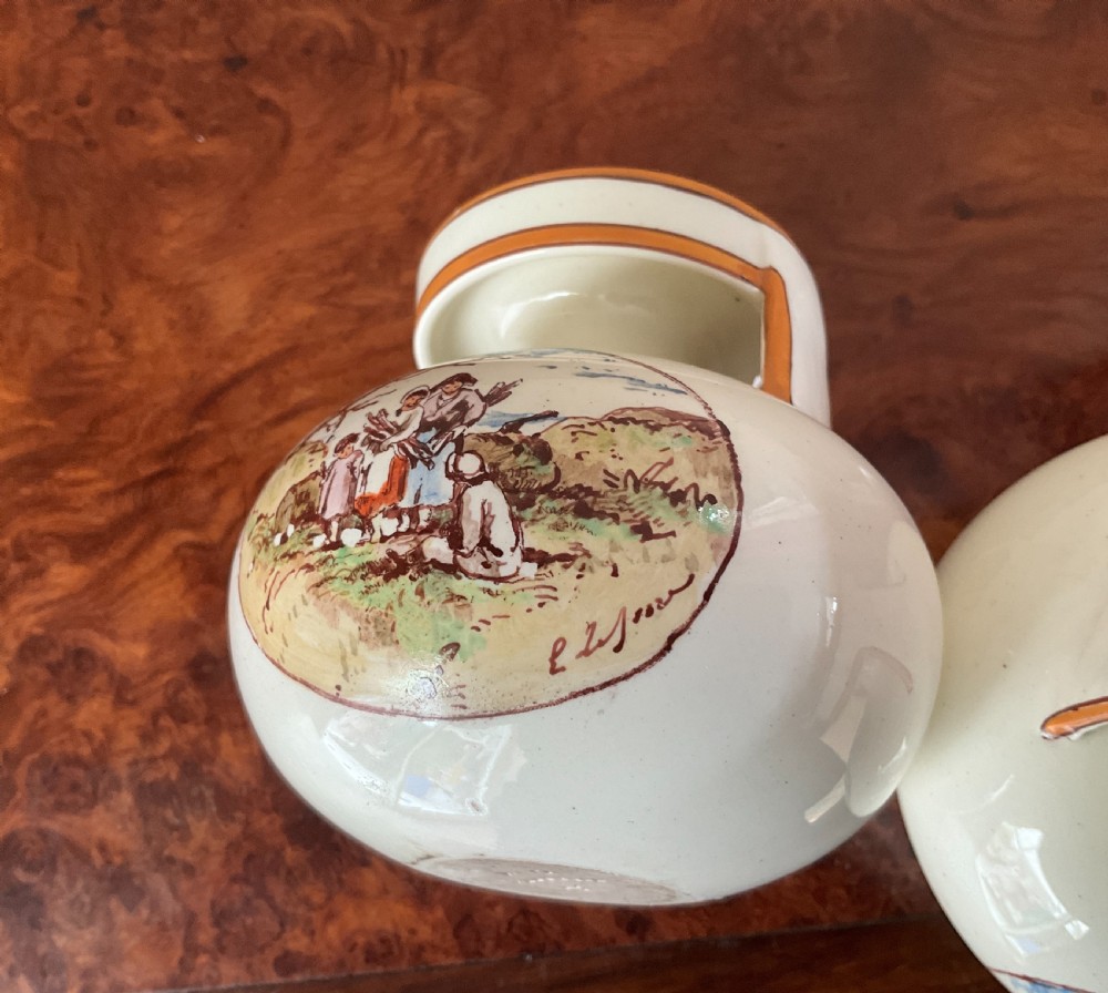 A pair of bulbous cream earthenware vases with orange-trimmed tops, decorated with painted oval cartouches depicting rural agricultural harvest scenes. View V