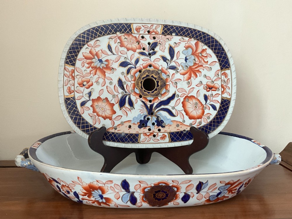A large oval white ironstone platter and matching pierced strainer insert decorated with dark blue, terracotta, and gold floral Imari patterns.