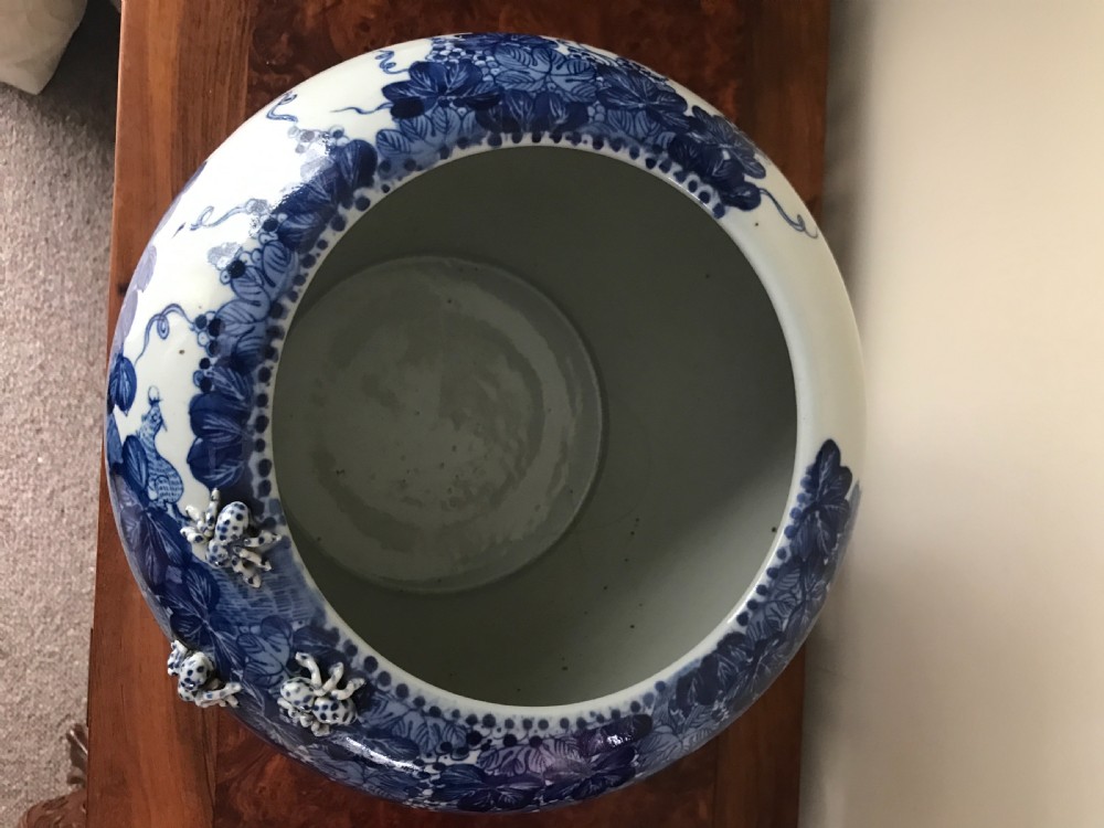 A rounded blue and white Japanese porcelain vase decorated with grapevine motifs and small three-dimensional relief creatures near the rim. View III