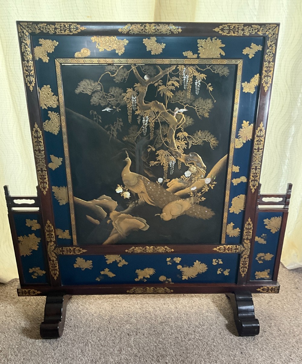 A Japanese single-panel standing screen decorated with gold lacquer peacock and wisteria motifs on a dark background, set within a carved wood frame.