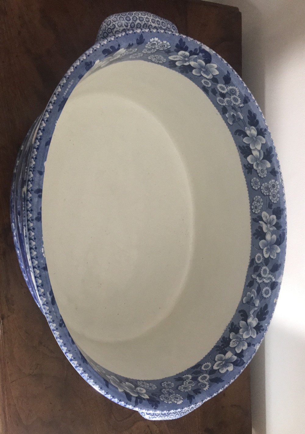 An oval blue and white transferware ceramic footbath featuring twin side handles and a detailed river landscape scene. View II