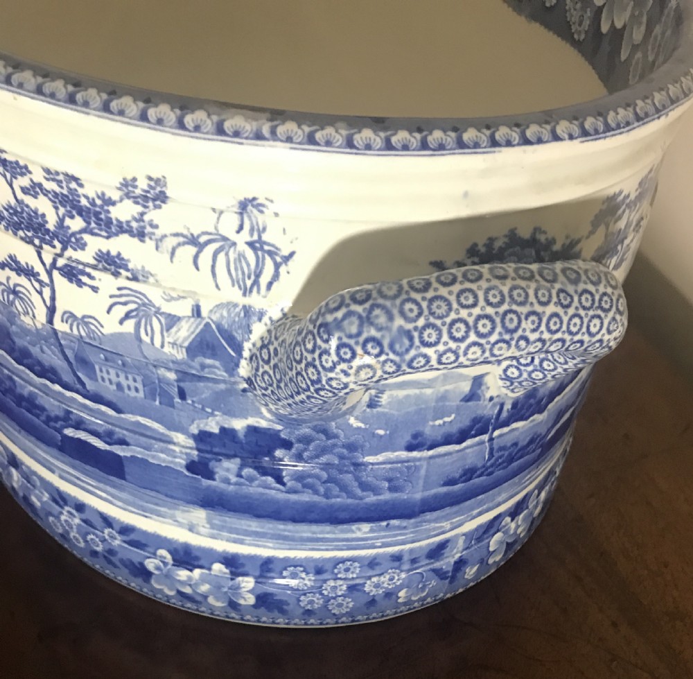 An oval blue and white transferware ceramic footbath featuring twin side handles and a detailed river landscape scene. View III