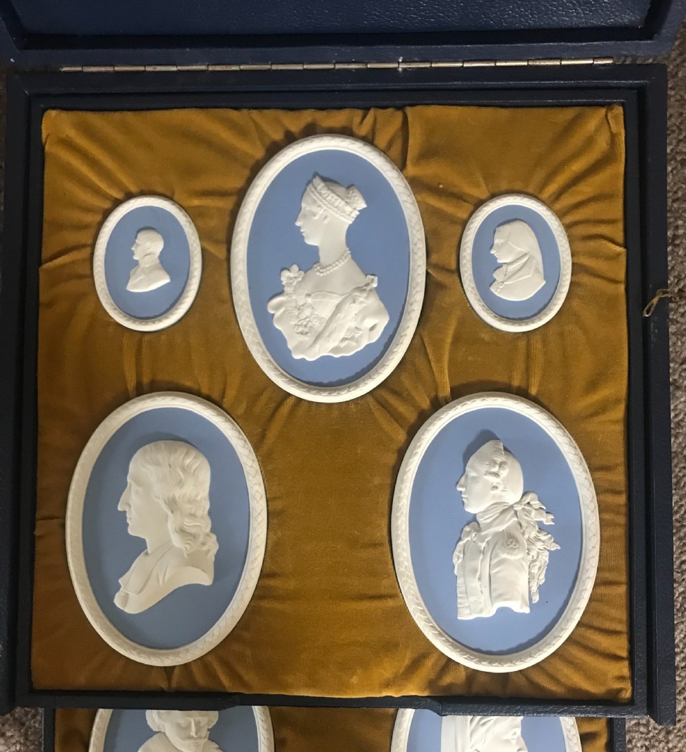 A set of blue and white Wedgwood jasperware oval portrait medallions depicting historical figures, housed in a gold velvet-lined presentation box with drawers. View II