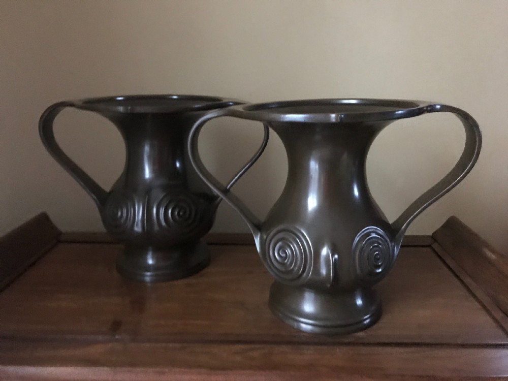 A pair of dark brown patinated bronze Japanese Mimikuchi vases featuring wide flaring rims, sweeping side handles, and relief spiral motifs on the body.