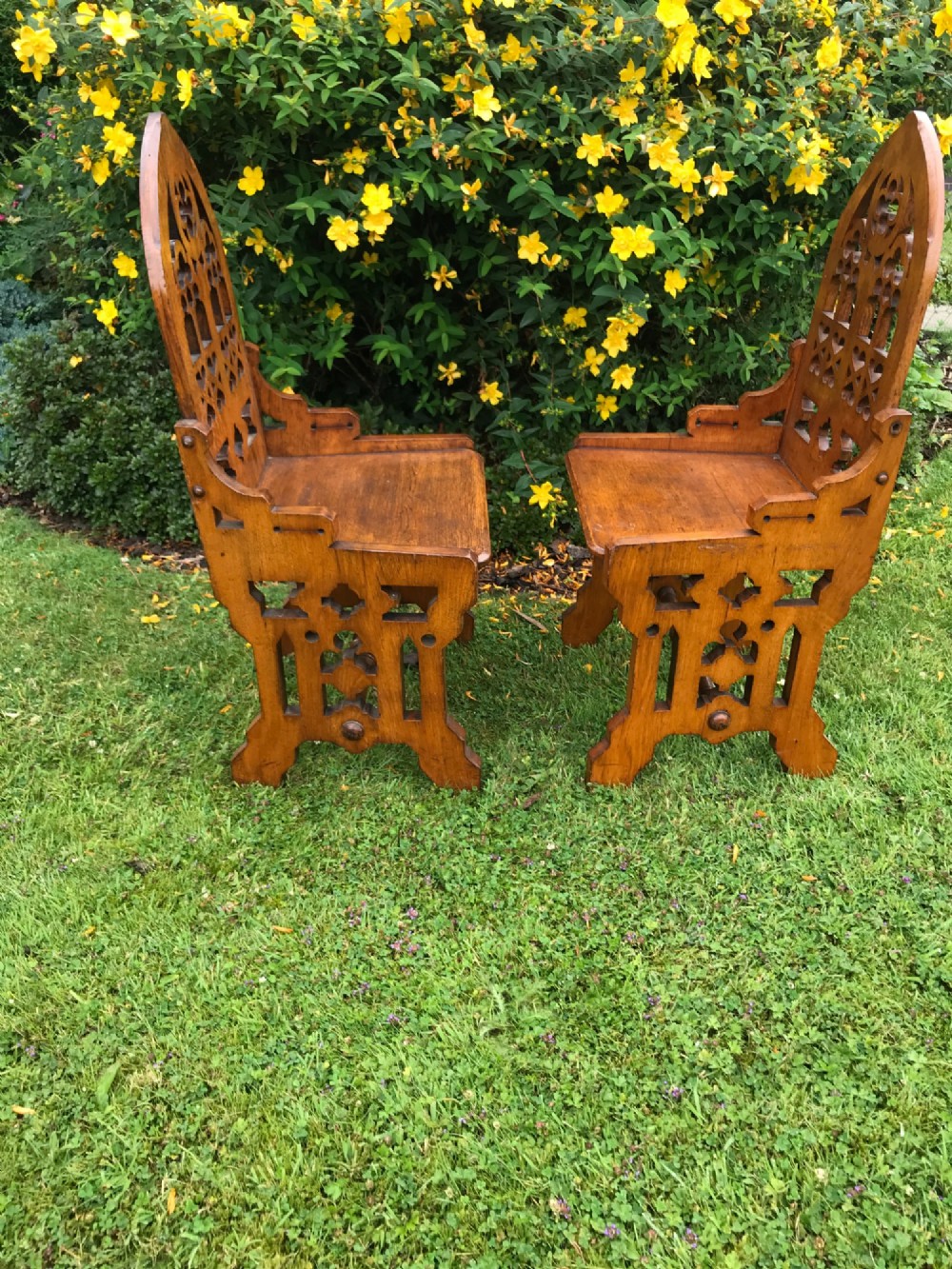A pair of carved oak Gothic Revival hall chairs featuring pointed arch backs with tracery cut-outs and solid wooden seats. View III