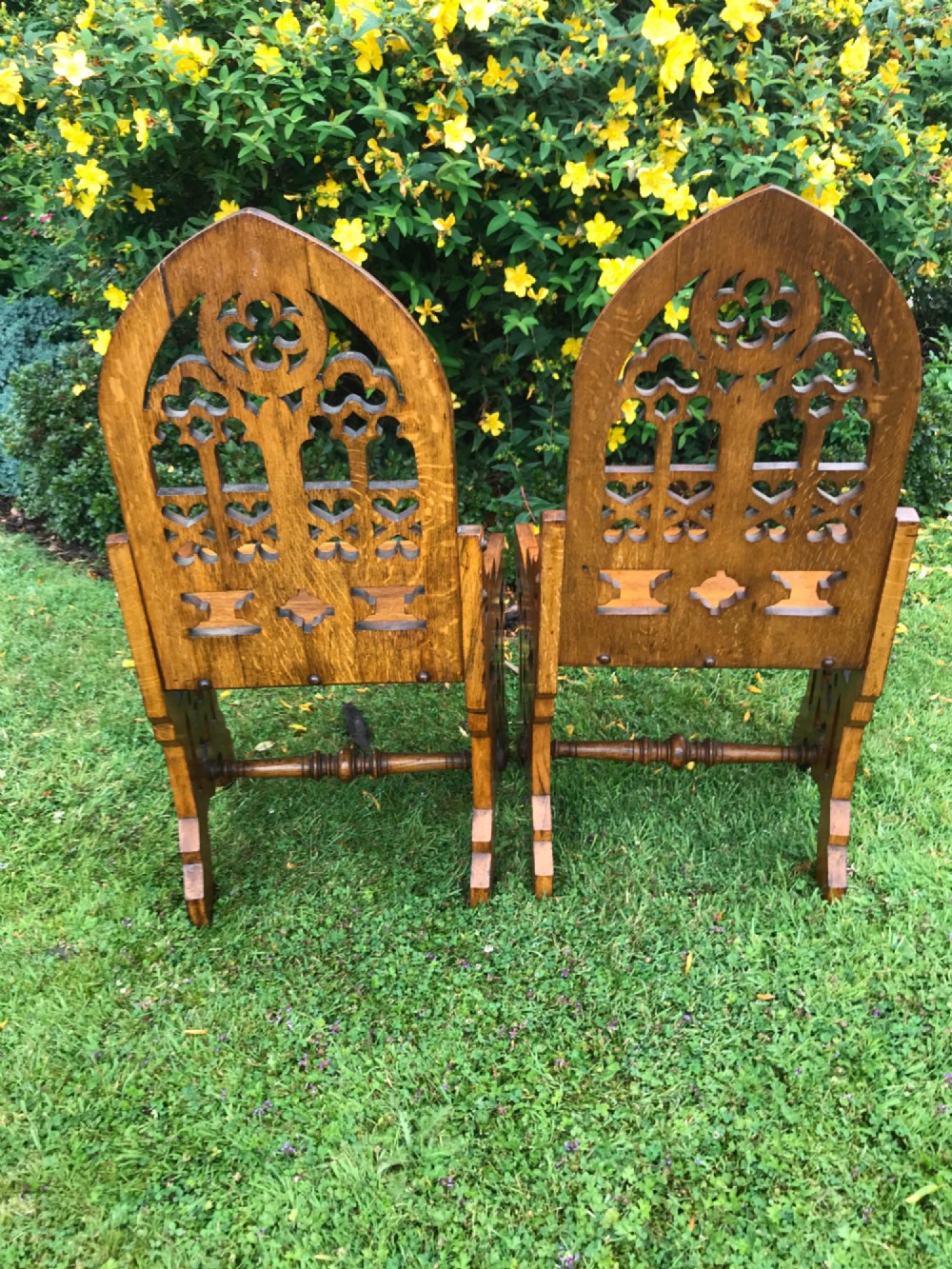 A pair of carved oak Gothic Revival hall chairs featuring pointed arch backs with tracery cut-outs and solid wooden seats. View IV