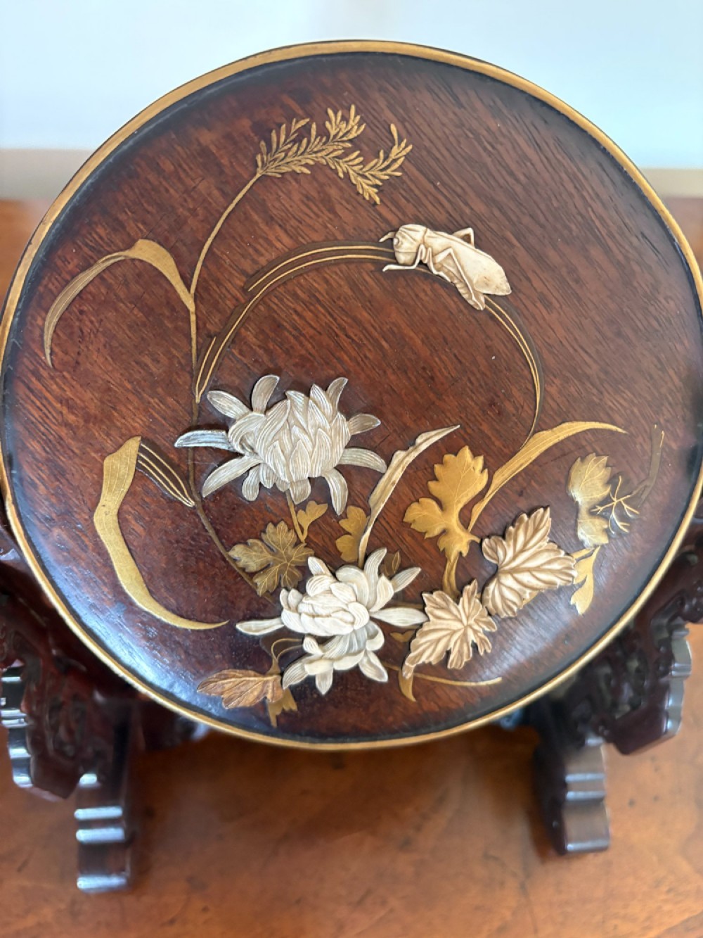 A circular dark wood Japanese table screen featuring raised mother-of-pearl floral and insect inlays, set within a carved hardwood stand. View VII