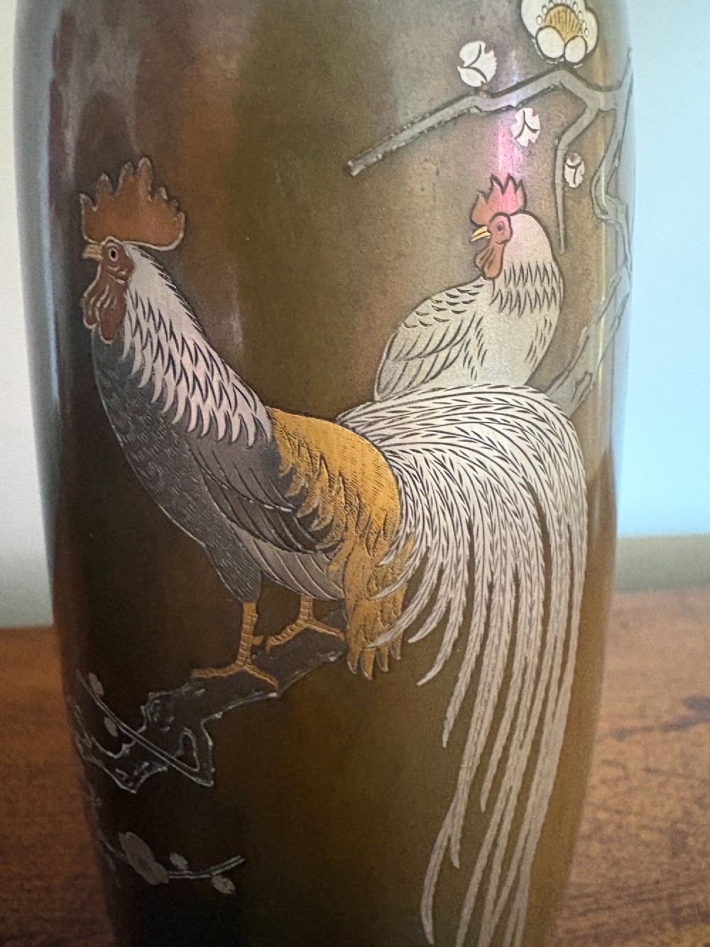 A Japanese Meiji period bronze vase featuring silver and gold inlay depicting a cockerel and hen perched on a flowering branch. View V