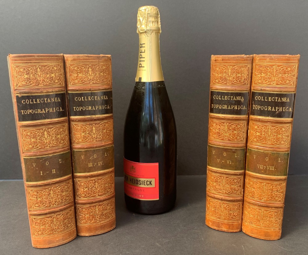 Four antique tan leather-bound volumes with ornate gold gilt decoration and dark title labels on the spines. View V