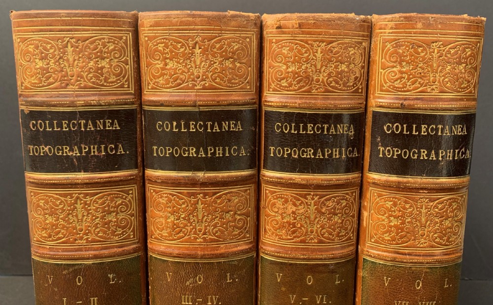 Four antique tan leather-bound volumes with ornate gold gilt decoration and dark title labels on the spines. View VI