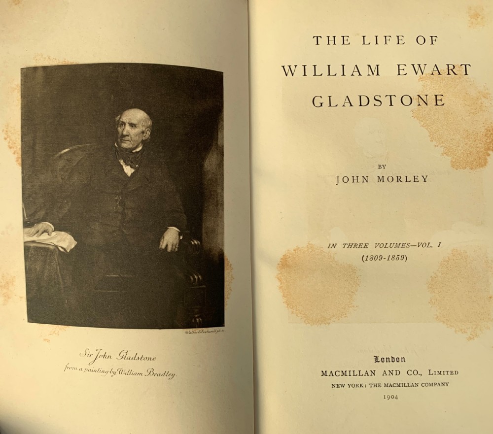 A three-volume set of Edwardian books titled The Life of W E Gladstone, bound in brown half-leather with red cloth sides and gilt spine ornamentation. View X