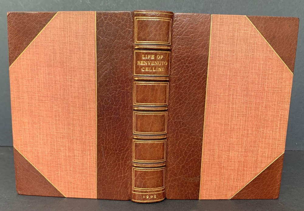 An Edwardian half-leather bound volume titled The Life of Benvenuto Cellini with gilt spine lettering, raised bands, and terracotta cloth boards. View II