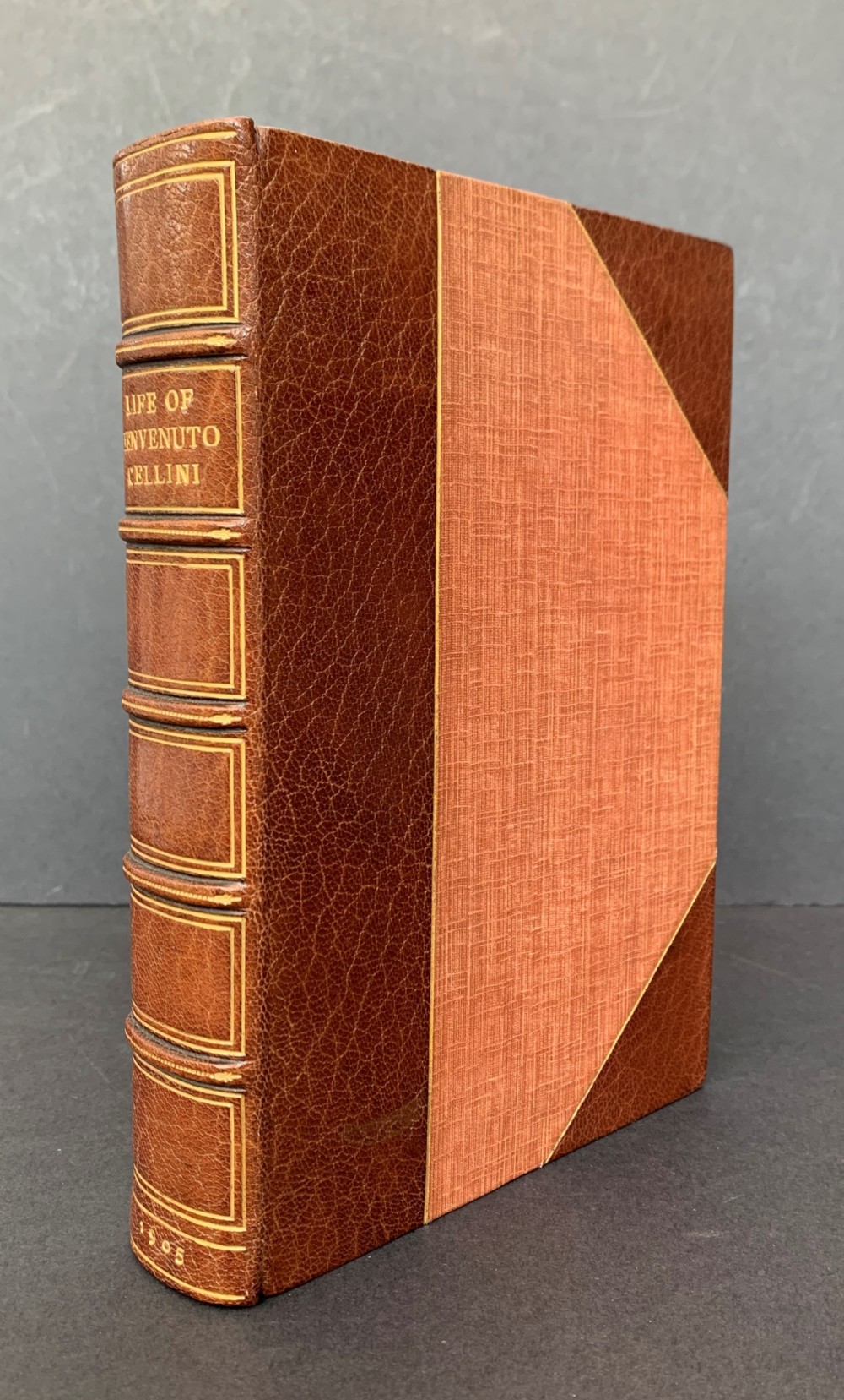 An Edwardian half-leather bound volume titled The Life of Benvenuto Cellini with gilt spine lettering, raised bands, and terracotta cloth boards.