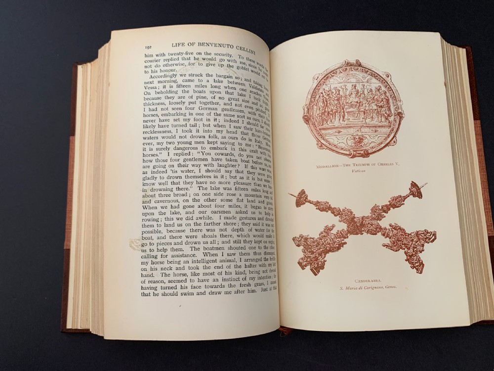 An Edwardian half-leather bound volume titled The Life of Benvenuto Cellini with gilt spine lettering, raised bands, and terracotta cloth boards. View XII