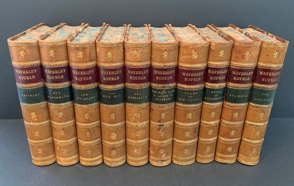 A set of ten Victorian tan leather-bound books titled Waverley Novels displayed side-by-side with gilt tooling and red and green spine labels.