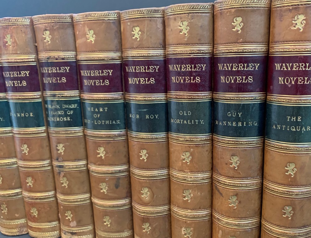 A set of ten Victorian tan leather-bound books titled Waverley Novels displayed side-by-side with gilt tooling and red and green spine labels. View VI