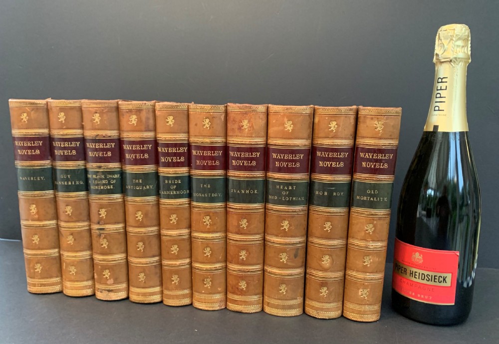 A set of ten Victorian tan leather-bound books titled Waverley Novels displayed side-by-side with gilt tooling and red and green spine labels. View XVI