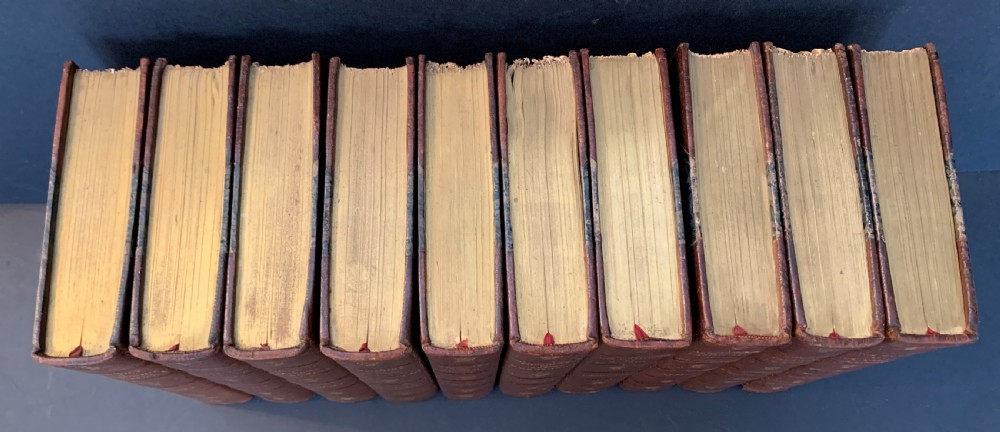 A collection of ten matching antique tan leather-bound books standing upright with gold leaf lettering on their spines. View II